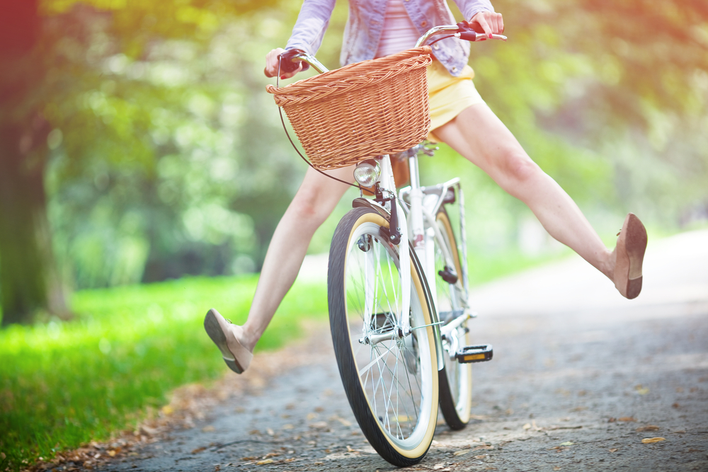 Woman Bikes With Legs Outstretched On Park Road